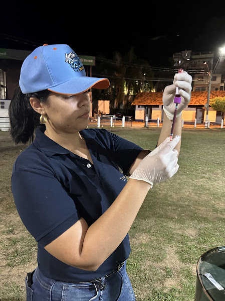 Médica veterinária de luvas brancas examinando um tubo de coleta de sangue